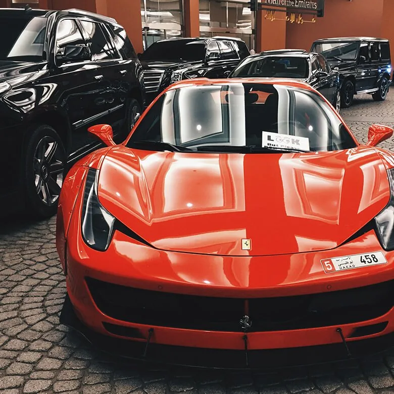 Ferrari vermelha entre carros importados